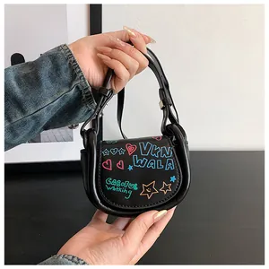 Gros plan d'un mini sac selle en cuir noir avec des graffitis colorés et des motifs d'étoiles