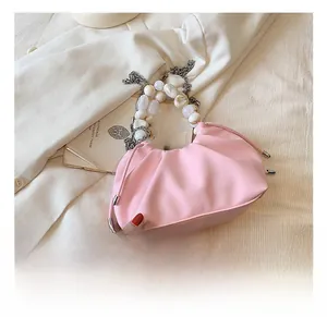 Detail of pink pleated bag featuring pearl handle and embossed brand logo branding