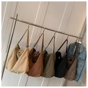 Detailed view of large canvas hobo bags in five colors hanging on a metal display rack