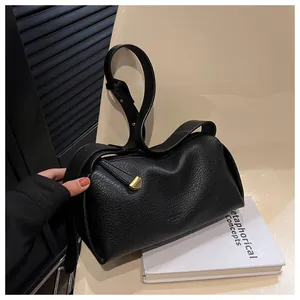 Close-up of black pebble grain leather handbag with gold geometric hardware and strap