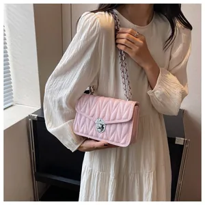 Detail of light pink V-quilted faux leather crossbody bag with silver chain strap