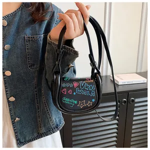 Détail d'un mini sac selle noir présentant des motifs de graffitis colorés et artistiques
