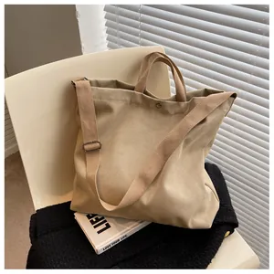 Detail view of khaki canvas tote bag with snap closure and wide adjustable shoulder strap