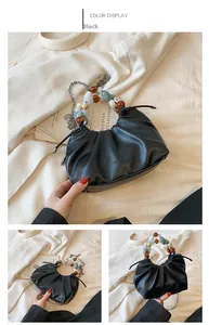 Detail of black pleated cloud bag with colorful beaded handle and metal chain strap