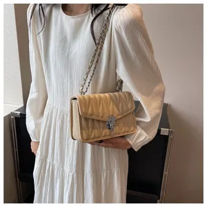 Detail of beige quilted shoulder bag with vertical wave pattern and silver chain strap