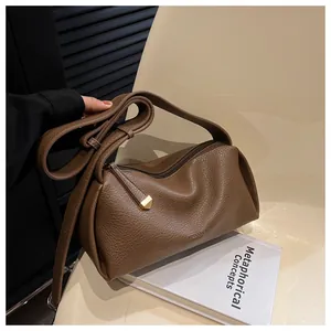 Close-up of brown litchi grain leather shoulder bag with gold metal hardware details