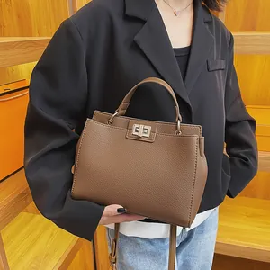 Detail view of brown pebbled leather handbag with silver twist lock and accordion sides