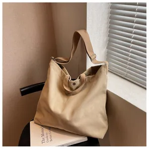 Detail of a large beige canvas tote bag with adjustable strap on a chair