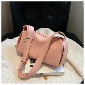 Detail of pink cylinder crossbody bag showing pebbled leather texture and wide strap