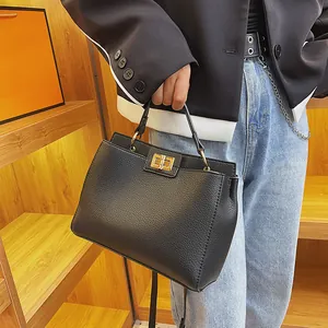 Detail of black lychee grain leather tote with gold twist-lock and fine chain strap