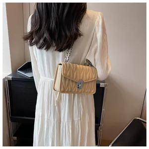 Detail of beige quilted shoulder bag with silver chain and metal turn-lock closure