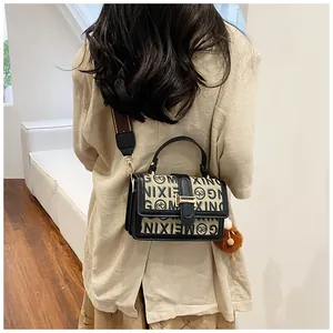 Detail showing the crossbody back view of a beige jacquard bag with black leather and plush ball