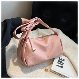 Detailed view of pink pebble grain crossbody bag with wide strap on a soft textured surface