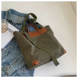 Detail of army green canvas tote with brown leather handles and adjustable shoulder strap