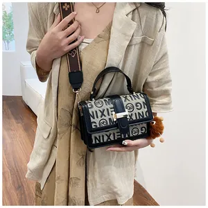 Detail of vintage canvas crossbody bag with leather trim and decorative pom-pom