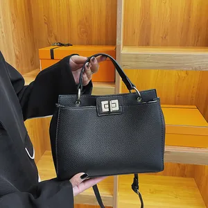 Detail of black lychee grain leather tote bag with silver clasp and adjustable strap