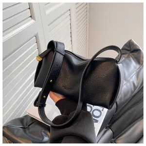 Detailed macro view of black lychee grain texture and gold hardware on the fashion bag