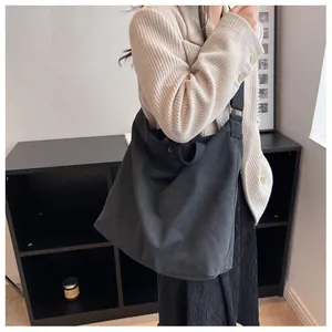 Close-up of a large black canvas tote bag worn as a shoulder bag on a female model
