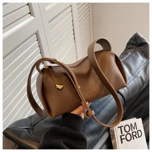 Detail shot of brown lychee grain leather cylinder bag with gold zippers and dual straps