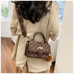 Detail of a brown checkered handbag with a gold metal clasp and a wide canvas strap