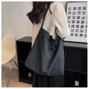 Lifestyle view of a large black canvas tote bag worn by a model in a modern interior