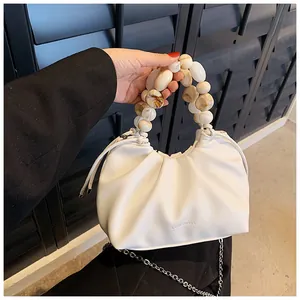 Detail of white pleated cloud bag with marble bead handle and Luomenisha logo branding