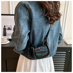 Détail d'un mini sac à bandoulière en cuir noir avec des motifs de graffitis colorés de style