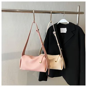 Detail view of pink and beige cylindrical bags with litchi grain texture and gold hardware