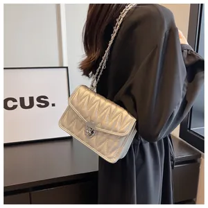 Close-up of a silver quilted crossbody bag with metal chain strap and turn-lock closure