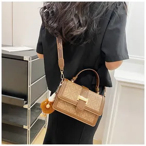 Close-up of brown monogram crossbody bag with metallic H buckle and fuzzy charm detail
