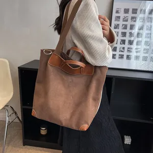 Brown large capacity canvas tote bag worn by a model in a minimalist modern interior