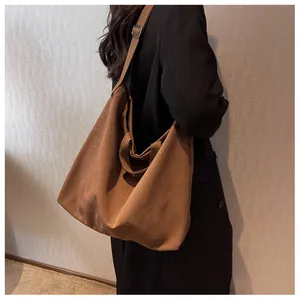 Brown canvas tote bag with adjustable strap shown on model for size perspective