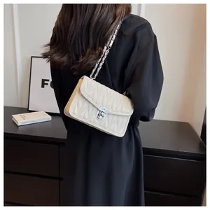 Close-up of cream quilted crossbody bag with silver chain strap and V-pattern stitching