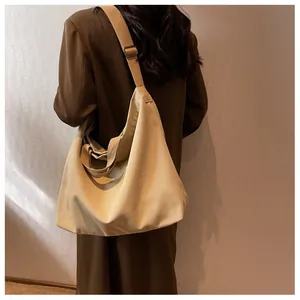 Model view of large canvas crossbody bag with adjustable wide strap in beige
