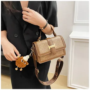 Detail of brown leather handbag with MEIXING logo pattern and gold metal buckle