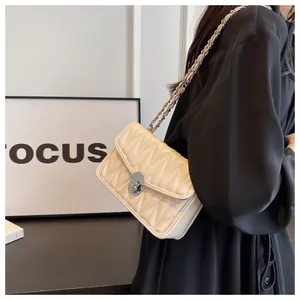Detail of beige quilted chain bag with silver twist lock on black dress