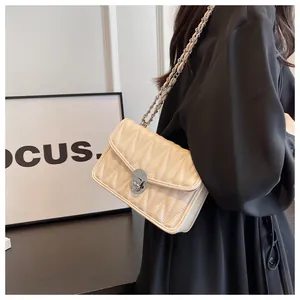 Chic beige quilted crossbody bag with silver chain strap shown on a black dress model