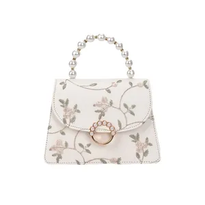 Trapezoid lace handbag with floral embroidery, pearl handle and metal ring clasp