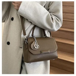 Detail of dark brown lychee leather handbag with silver pendant on indoor stairs