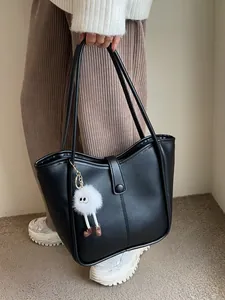 Classic black faux leather tote bag with plush charm, perfect for daily commuting use