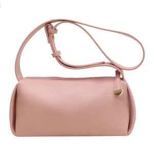 Minimalist pink soft textured crossbody bag with a wide strap and golden metal pendant