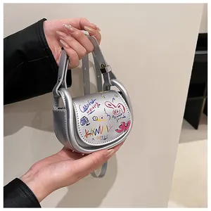 Détail du mini sac selle argenté avec graffitis artistiques et une poignée circulaire