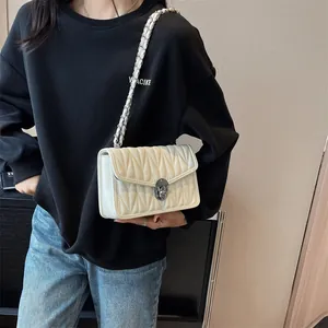 Chic cream quilted crossbody chain bag featuring V-shaped stitching and metal turn-lock