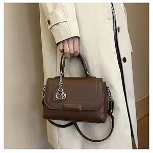 Close-up of brown pebbled leather handbag featuring a silver swan charm and top handle