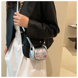 Détail du mini sac selle argenté avec graffitis colorés et poignée en U en métal