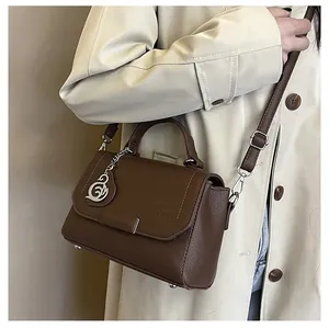 Detail of dark brown pebble leather bag with silver swan pendant and adjustable strap