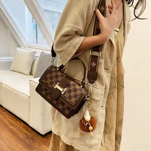Classic brown checkered small square bag with floral shoulder strap on a beige dress