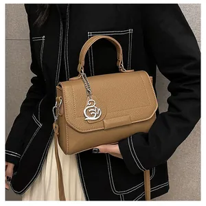 Macro detail of tan lychee grain leather handbag with silver swan charm and top handle