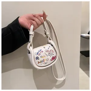 Détail du mini sac selle blanc avec graffiti artistiques colorés et motifs dessinés