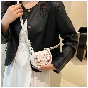Détail du mini sac selle blanc avec graffitis colorés et fine bandoulière en cuir